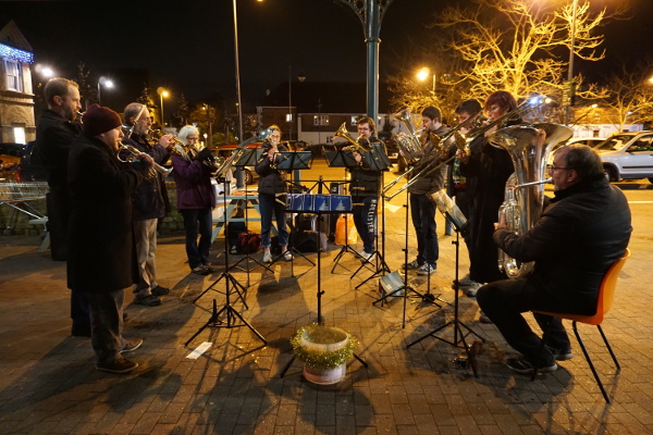 Small band carolling outside the supermarket with a donation bucket